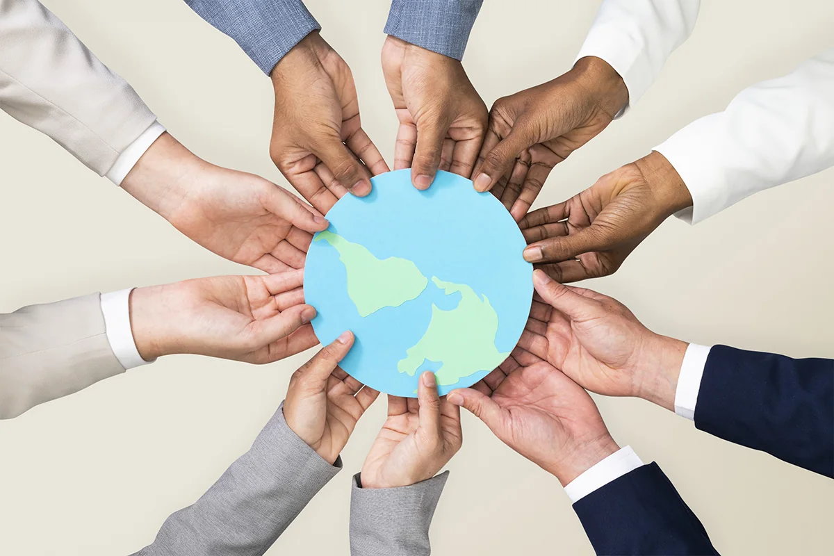 Many hands holding a small globe together